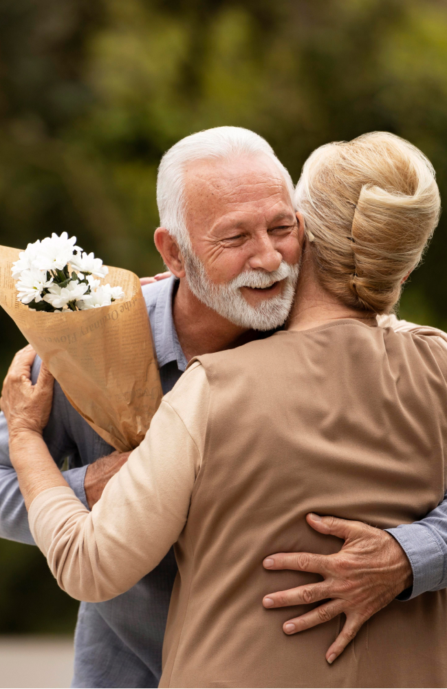 Senhor idoso feliz enquanto abraça sua esposa, uma senhora idosa de cabelos loiros.
